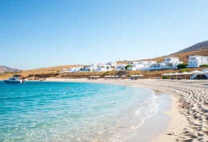 Αμμουδιά με τιρκουάζ νερά και λευκά σπίτια σε κυκλαδίτικο νησί